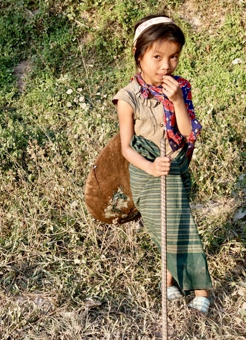 Fillette avec une barre à mine pour creuser le sol et une bâtée