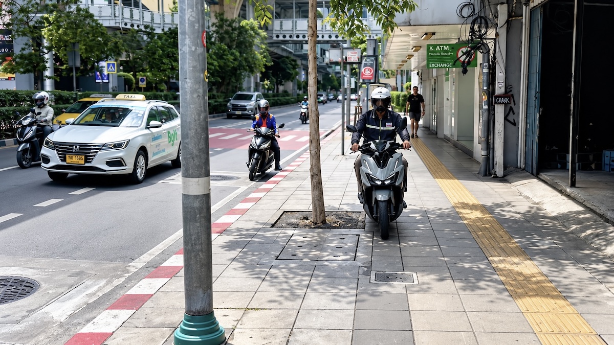 Une moto circule sur un trottoir de Bangkok